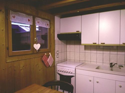a kitchen with white cabinets and a table and a sink at Demi-Chalet Le Bief --Prox pistes in Les Carroz d'Araches