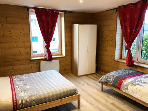 a bedroom with wooden walls and a bed with red curtains at Chez Léa et Lolo - Le Nordique in Gérardmer