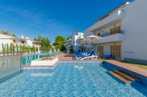 a villa with a swimming pool with chairs and a house at Venecia Apartments in Port d'Alcudia