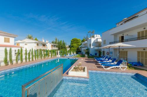 a swimming pool with chairs and umbrellas at a resort at Venecia Apartments in Port d'Alcudia