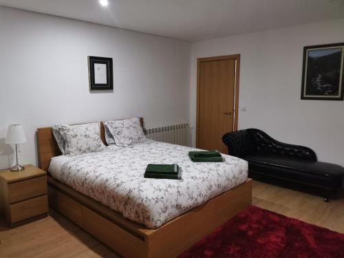 a bedroom with a bed and a black chair at Isabel do Couto - casa de charme in Castro Daire