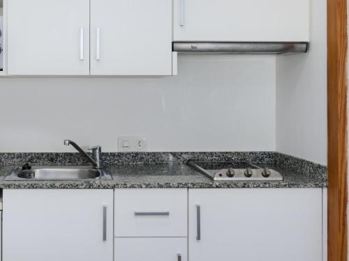 a kitchen with white cabinets and a sink at Venecia Apartments in Port d'Alcudia