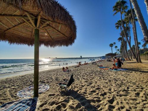 a beach with a straw umbrella and people on the sand at Sea Horse Resort in San Clemente