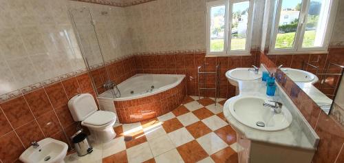 a bathroom with two sinks and a tub and a toilet at Sunset Villa by Laranjal Rentals in Olhos de Água