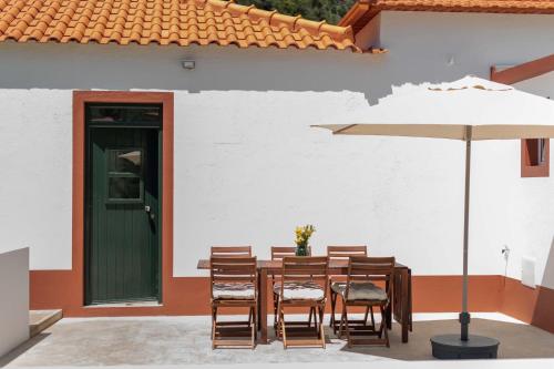 a wooden table with chairs and an umbrella at Casa do Bago in São Vicente