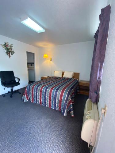 a hotel room with a bed and a chair at Regency Inn Comanche in Comanche