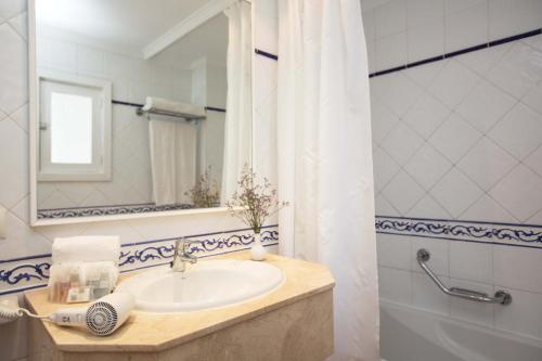 ein Badezimmer mit einem Waschbecken, einem Spiegel und einer Badewanne in der Unterkunft Gavimar Cala Gran Hotel and Apartments in Cala d´Or