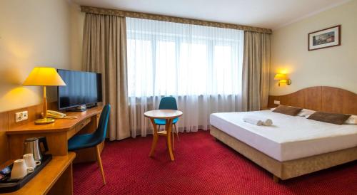 a hotel room with a bed and a desk and a television at Best Western Hotel Portos in Warsaw