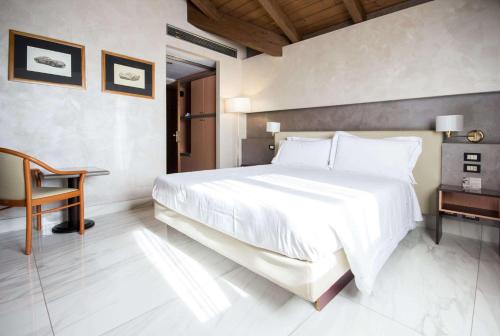 a bedroom with a large white bed and a chair at Best Western Modena District in Campogalliano