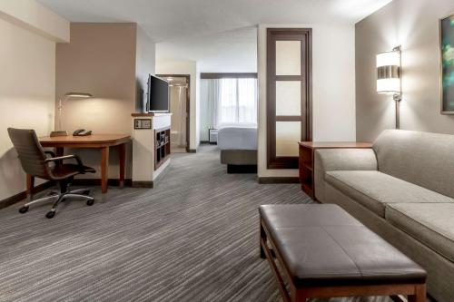 um quarto de hotel com um sofá, uma secretária e uma cama em Hyatt Place Richmond Arboretum em Richmond