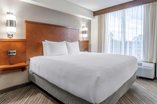 a large white bed in a hotel room with a window at Hyatt Place Richmond Arboretum in Richmond