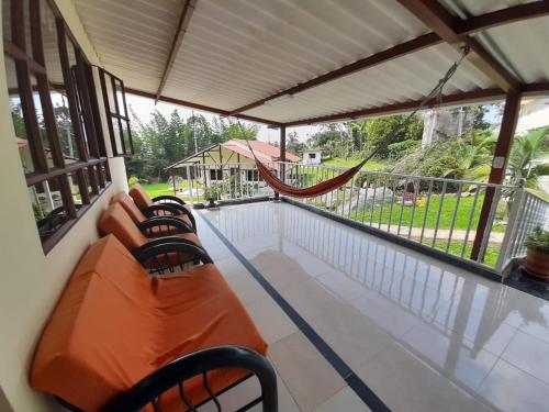 a porch with two chairs and a hammock on it at Finca Villa Elenita in Sasaima
