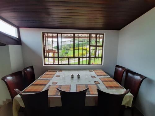 une table à manger avec des chaises et une fenêtre dans l'établissement Finca Villa Elenita, à Sasaima