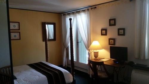 a bedroom with a bed and a desk with a lamp at Logis-Hôtel Côté-Rivage in Badefols-sur-Dordogne