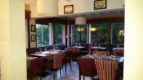 a dining room with tables and chairs and windows at Logis-Hôtel Côté-Rivage in Badefols-sur-Dordogne