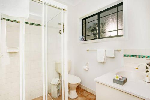 a white bathroom with a shower and a toilet at Seascape The Haven in Scotts Head