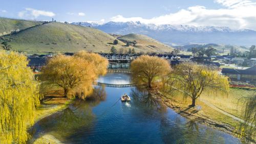 a boat on a river with trees and mountains at Marsden Lake Resort Central Otago in Cromwell