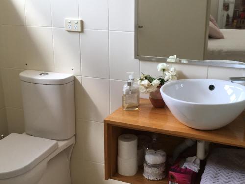 W łazience znajduje się umywalka, toaleta i lustro. w obiekcie By the Lake - Lake Macquarie w mieście Teralba