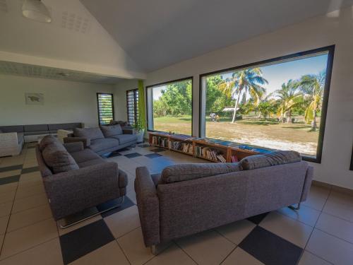 a large living room with couches and large windows at Auberge de Poé in Bourail