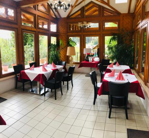 a restaurant with red tables and chairs and windows at Alpenpension Gasthof in Ratten