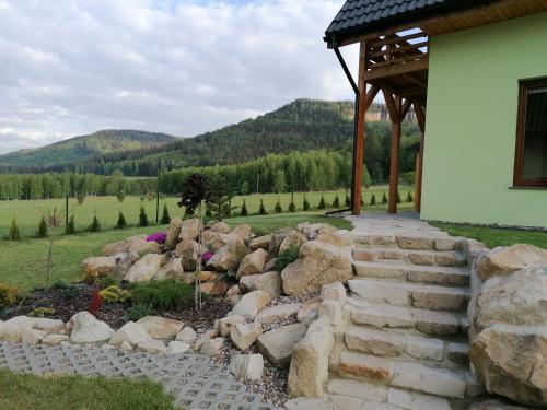 a stone walkway leading to a house with a rock wall at Domki pod Derkaczem in Wünschelburg
