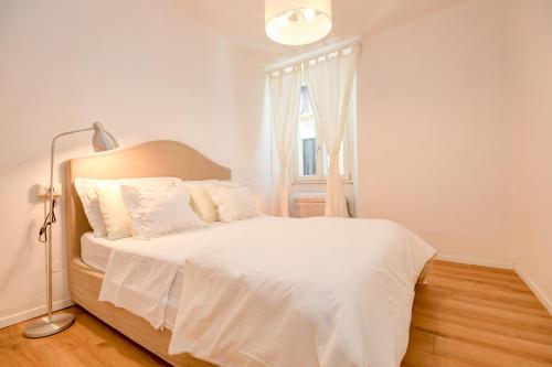 a bedroom with a white bed with a lamp and a window at BELLAVISTA - Garda Leisure in Salò