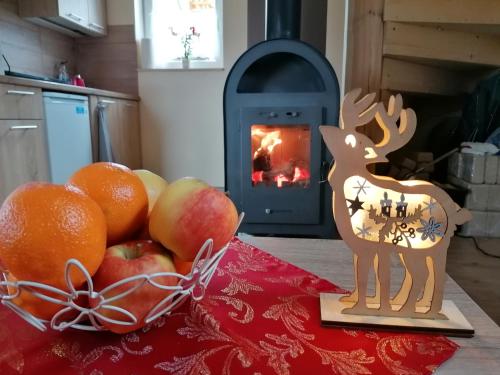 a table with fruit and a statue of a deer in front of a stove at Domki pod Derkaczem in Wünschelburg