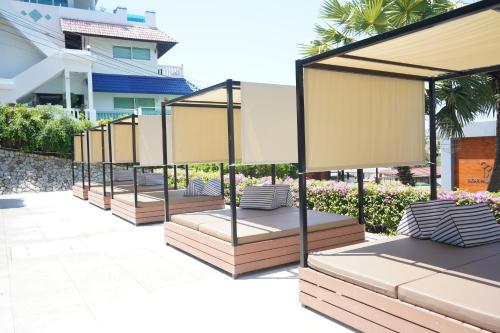 a row of benches with umbrellas in front of a building at Sugar Palm Grand Hillside - SHA Plus in Kata Beach