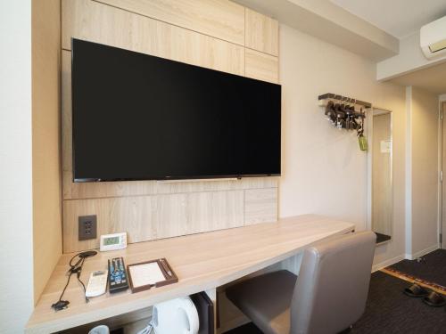Habitación con escritorio y TV en la pared. en Super Hotel Hida Takayama en Takayama