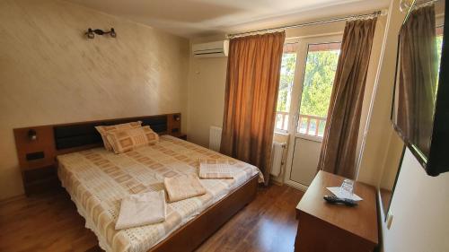 a bedroom with a bed and a large window at Family Hotel The Rocks in Belogradchik