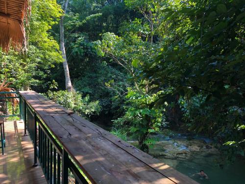 a wooden bridge over a river in a forest at LePont Mu Waterfall Bungalow in Hòa Bình
