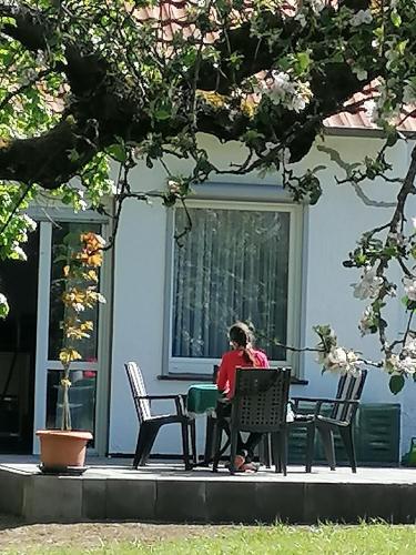 una mujer sentada en una mesa frente a un edificio en FEWO-ATLANTA Reinhardshausen, en Reinhardshausen