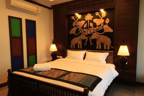 a bedroom with a large bed with a painting on the wall at Baan Ratchiangsaen in Chiang Mai