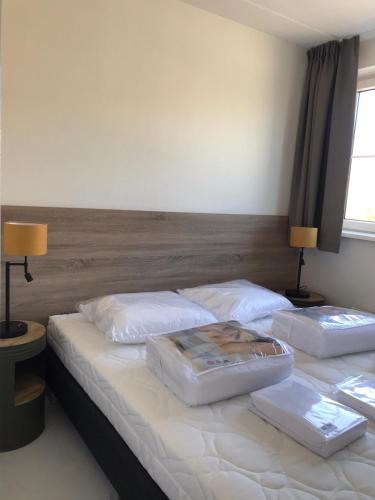 two twin beds in a bedroom with two lamps at de Putter in Hollum