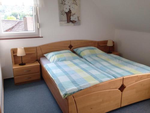 1 dormitorio con cama de madera con 2 almohadas y ventana en Ferienwohnung Waldruhe, en Hessisch Oldendorf