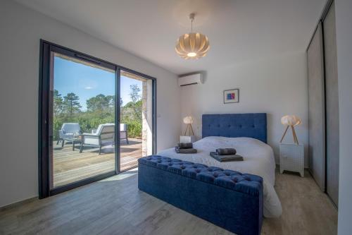 een slaapkamer met een blauw bed en een glazen schuifdeur bij Villa calme luxueuse et proche plage saint-cyprien in Lecci