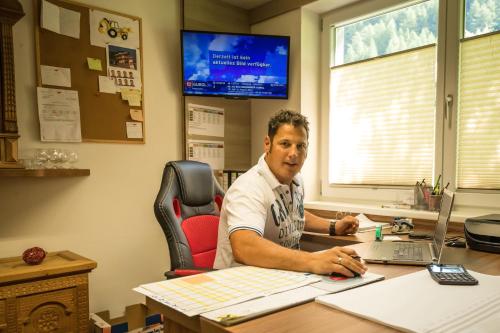 a man sitting at a desk with a laptop computer at Apart Praxmarer in Sölden
