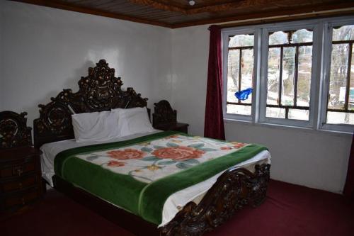 1 dormitorio con 1 cama con edredón verde en Track View Hotel, en Murree