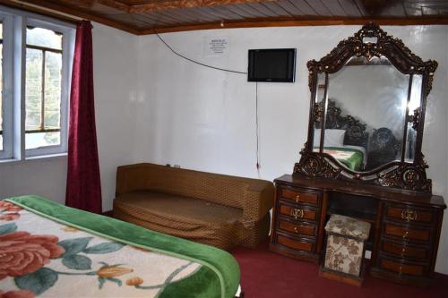 1 dormitorio con espejo, 1 cama y vestidor en Track View Hotel, en Murree