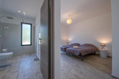 een slaapkamer met een bed en een badkamer met een wastafel bij Villa calme luxueuse et proche plage saint-cyprien in Lecci