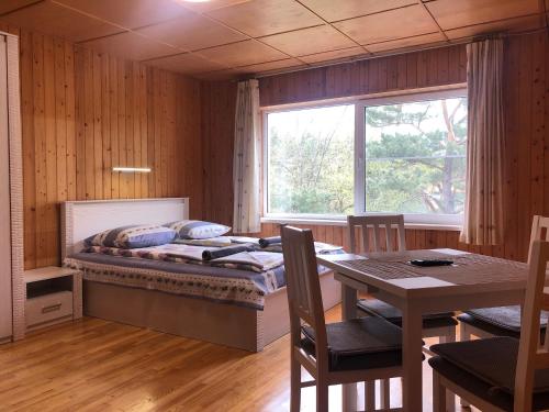 Schlafzimmer mit einem Bett, einem Tisch und einem Fenster in der Unterkunft Cunami in Nida