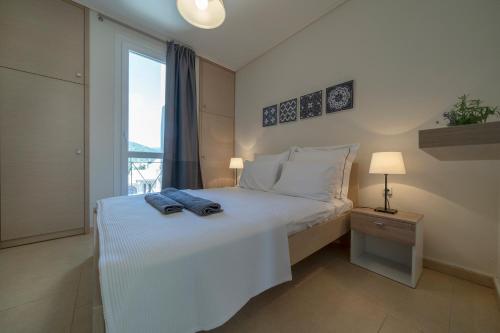 a bedroom with a white bed with a window at Villa Luminous in Iraklitsa