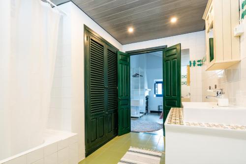 La salle de bains est pourvue de portes vertes, d'un lavabo et d'une baignoire. dans l'établissement Limonero bnb, à Gualchos