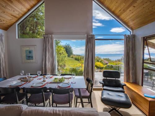 a dining room with a table and chairs and a large window at Kanuka House - Kaiteriteri Holiday Home in Kaiteriteri