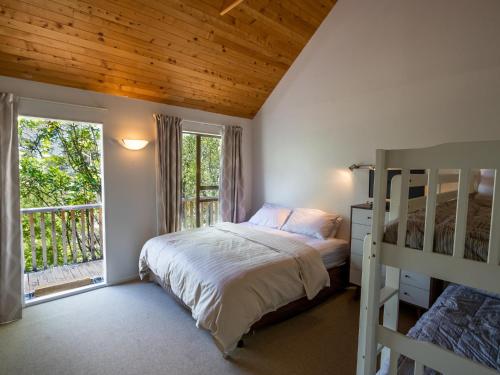a bedroom with a bunk bed and a balcony at Kanuka House - Kaiteriteri Holiday Home in Kaiteriteri