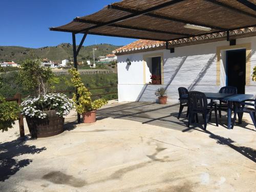 patio con tavolo e sedie sotto un tetto di Casa Los Ruices a Benajarafe