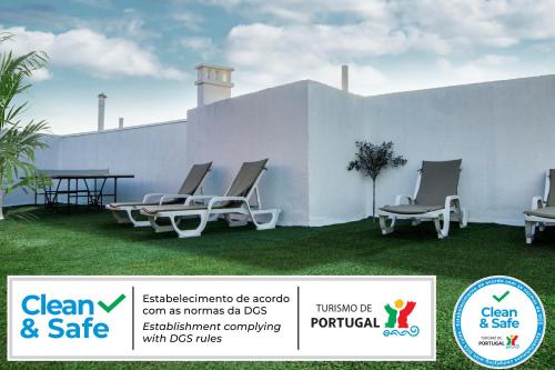 a group of chairs sitting on a lawn next to a white wall at LivingPorto Boavista in Porto