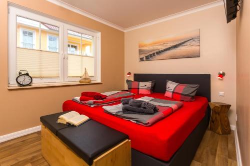オストゼーバート・カールスハーゲンにあるWaldperleのベッドルーム1室(赤いシーツを使用した大型ベッド1台付)