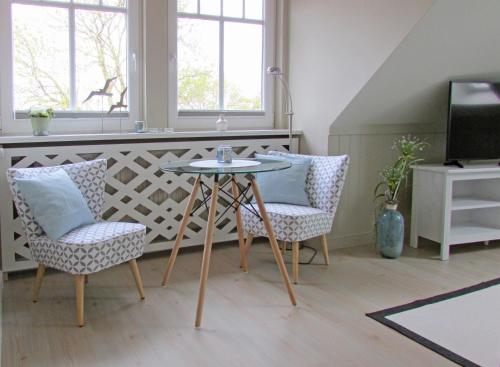 a living room with two chairs and a table and a tv at Gästehaus Muhl in Strukkamp auf Fehmarn