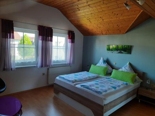 バート・ヴァルトゼーにあるFerienwohnung beim Riedのベッドルーム1室(緑の枕が付くベッド1台、窓2つ付)